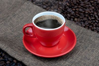 Red cup of Cafe Brasileiro Extraforte coffee on coffee beans background. 