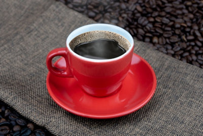 Red cup of Cafe Brasileiro Extraforte coffee on coffee beans background.