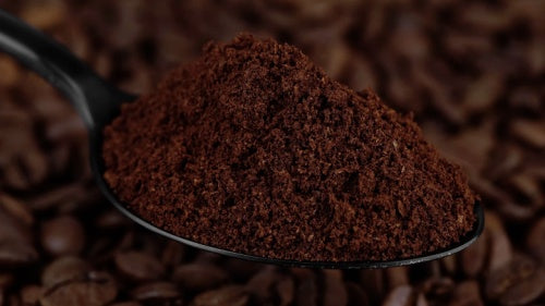 ground Cafe Brasileiro Tradicional coffee in black spoon and coffee beans on background