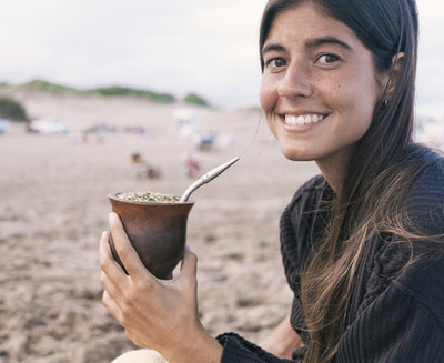 woman drinking cruz de malta yerba mate on the beach