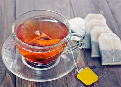 Glass mug of stone breaker tea, tea bags on table