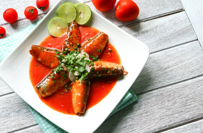 sardines in tomato sauce with limes on white plate