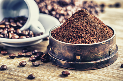 Ground coffee with coffee beans and mug on wood table