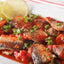Sardines in spicy tomato sauce on white plate with lemon
