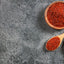 alicante aji triturado in a wood bowl and spoon, red peppers