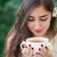 Woman with flower behind her ear drinking cup of tea