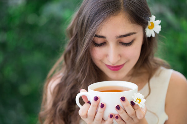 Woman with flower behind her ear drinking cup of tea