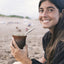 woman drinking cruz de malta yerba mate on the beach