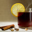 glass mug with té, canela y clavo with lemon slice, cinnamon and cloves on table 