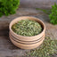 Bowl with dry parsley on wooden table