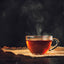 A Cup of freshly brewed tea,escaping steam darker background.